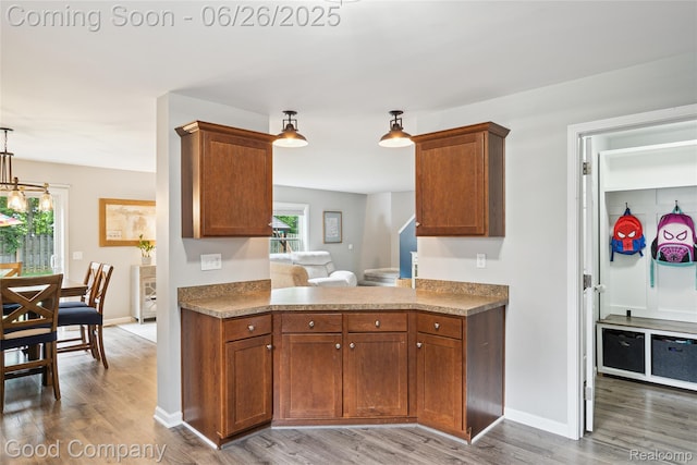 1123 Tartan Ln, Walled Lake, MI 48390 - kitchen featuring wood finished floors, brown cabinets, and hanging light fixtures