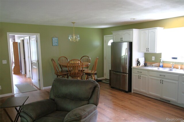 12850 E Rd, Burt, MI 48417 - kitchen featuring freestanding refrigerator, a chandelier, white cabinetry, and light wood-type flooring