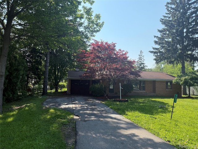 1321 Rainbow Dr, Saginaw, MI 48638 - view of front of house featuring asphalt driveway, an attached garage, a front lawn, and brick siding
