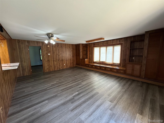 1321 Rainbow Dr, Saginaw, MI 48638 - empty room featuring wood walls, a ceiling fan, dark wood-type flooring, and an AC wall unit