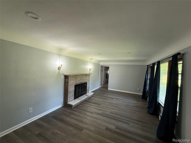 1321 Rainbow Dr, Saginaw, MI 48638 - unfurnished living room with dark wood-style flooring and a stone fireplace