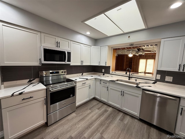 1321 Rainbow Dr, Saginaw, MI 48638 - kitchen with stainless steel appliances, decorative backsplash, light wood-style floors, recessed lighting, and white cabinetry