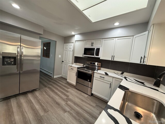 1321 Rainbow Dr, Saginaw, MI 48638 - kitchen with appliances with stainless steel finishes, a baseboard heating unit, light stone counters, recessed lighting, and tasteful backsplash