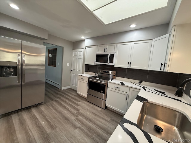 1321 Rainbow Dr, Saginaw, MI 48638 - kitchen featuring appliances with stainless steel finishes, recessed lighting, wood finished floors, light stone countertops, and a baseboard heating unit