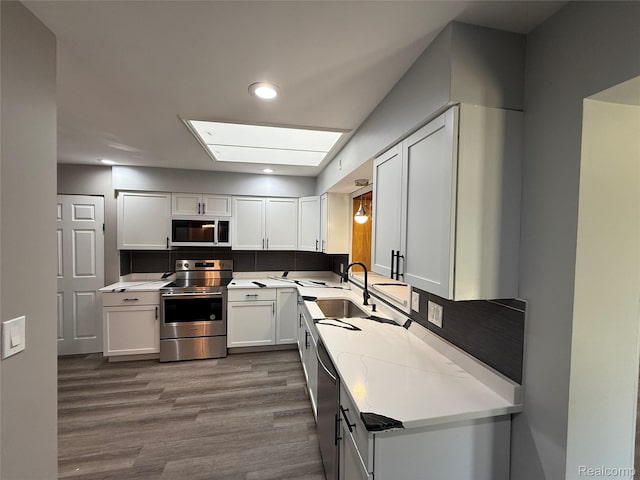 1321 Rainbow Dr, Saginaw, MI 48638 - kitchen with appliances with stainless steel finishes, dark wood-style flooring, recessed lighting, white cabinetry, and light countertops