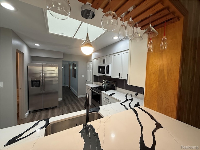 1321 Rainbow Dr, Saginaw, MI 48638 - kitchen featuring appliances with stainless steel finishes, dark wood finished floors, white cabinetry, light stone countertops, and decorative light fixtures