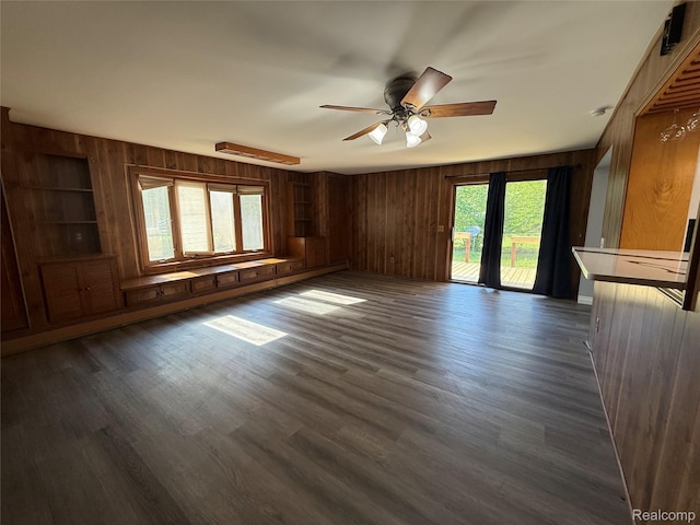 1321 Rainbow Dr, Saginaw, MI 48638 - unfurnished living room featuring wood walls, ceiling fan, and dark wood-style floors