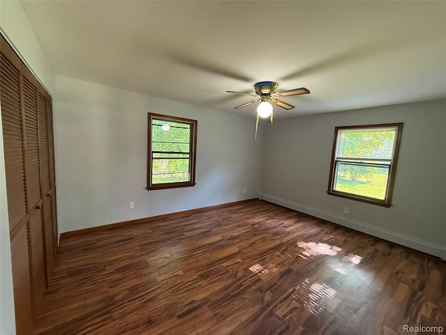 1321 Rainbow Dr, Saginaw, MI 48638 - unfurnished bedroom with multiple windows, a closet, dark wood-style floors, and a ceiling fan