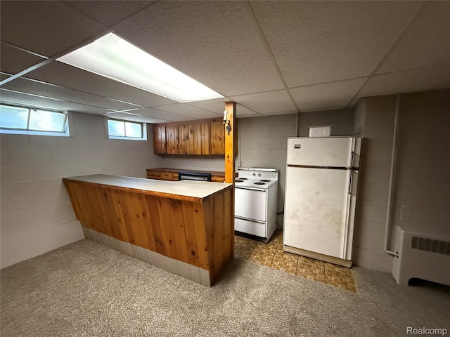 1321 Rainbow Dr, Saginaw, MI 48638 - kitchen with white appliances, a peninsula, a paneled ceiling, brown cabinets, and concrete block wall