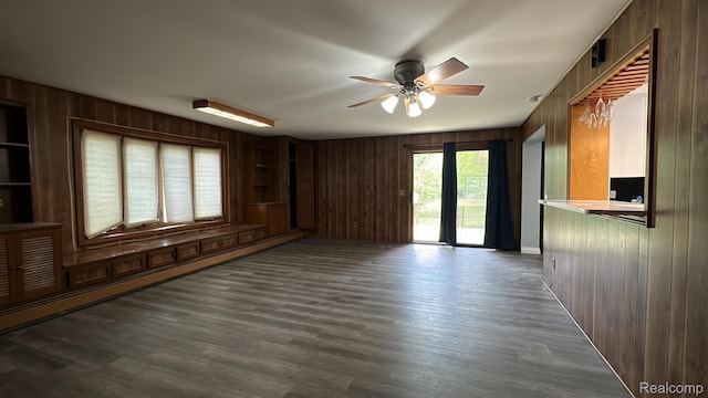 1321 Rainbow Dr, Saginaw, MI 48638 - unfurnished room with wooden walls, a ceiling fan, and dark wood-style flooring