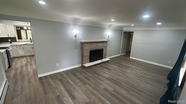 1321 Rainbow Dr, Saginaw, MI 48638 - unfurnished living room with dark wood finished floors, recessed lighting, a stone fireplace, and a baseboard heating unit
