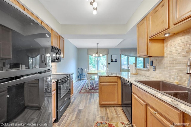210 Mary St, Flushing, MI 48433 - kitchen with black appliances, light wood-style floors, tasteful backsplash, a peninsula, and a chandelier