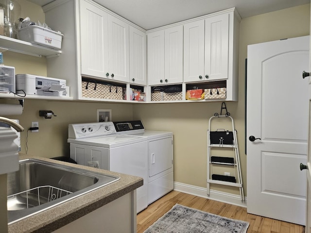 1005 W Lake St, Tawas City, MI 48763 - laundry room with independent washer and dryer, light wood-style floors, and cabinet space