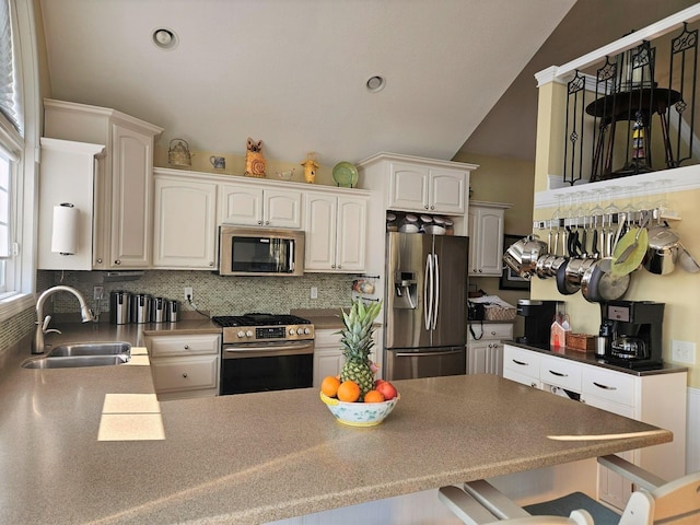 1005 W Lake St, Tawas City, MI 48763 - kitchen featuring appliances with stainless steel finishes, a peninsula, backsplash, a kitchen bar, and white cabinets
