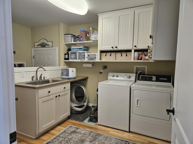 1005 W Lake St, Tawas City, MI 48763 - laundry area featuring washing machine and clothes dryer, light wood-type flooring, and cabinet space