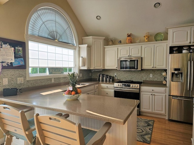1005 W Lake St, Tawas City, MI 48763 - kitchen featuring stainless steel appliances, decorative backsplash, a breakfast bar, white cabinetry, and light wood-type flooring