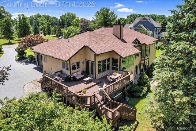 2985 Dana Pointe Dr, Pinckney, MI 48169 - back of property featuring a shingled roof, a wooden deck, a chimney, asphalt driveway, and a garage