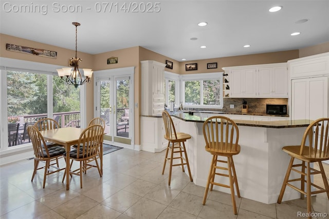 2985 Dana Pointe Dr, Pinckney, MI 48169 - kitchen featuring black microwave, healthy amount of natural light, tasteful backsplash, white cabinets, and recessed lighting