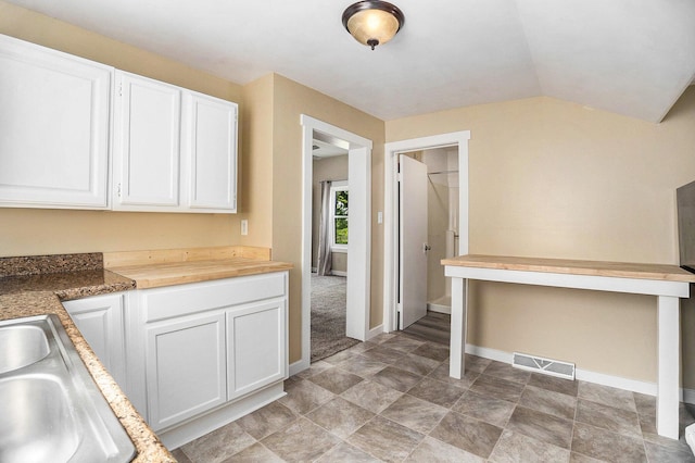 705 E Dowland St, Ludington, MI 49431 - kitchen featuring white cabinets, vaulted ceiling, and butcher block counters