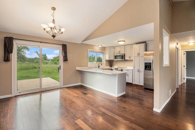 8175 Chamberlin Rd, Dexter, MI 48130 - kitchen featuring appliances with stainless steel finishes, a peninsula, light countertops, dark wood-style floors, and high vaulted ceiling
