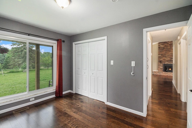 8175 Chamberlin Rd, Dexter, MI 48130 - unfurnished bedroom featuring dark wood-style floors, a closet, and a fireplace