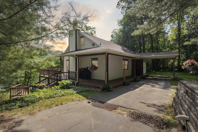 6860 Ashley Ave NE, Belding, MI 48809 - property exterior at dusk featuring a chimney, a wooden deck, and an attached carport