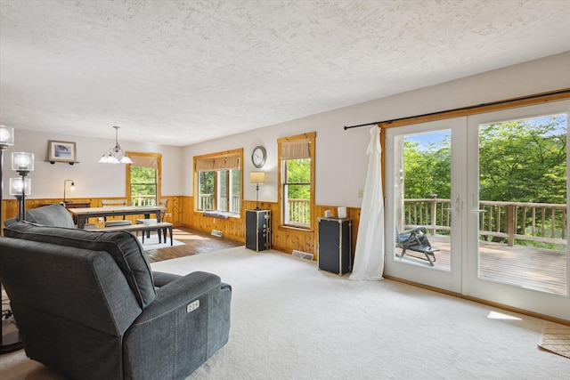 6860 Ashley Ave NE, Belding, MI 48809 - carpeted living area featuring a wainscoted wall, wooden walls, a textured ceiling, and a chandelier