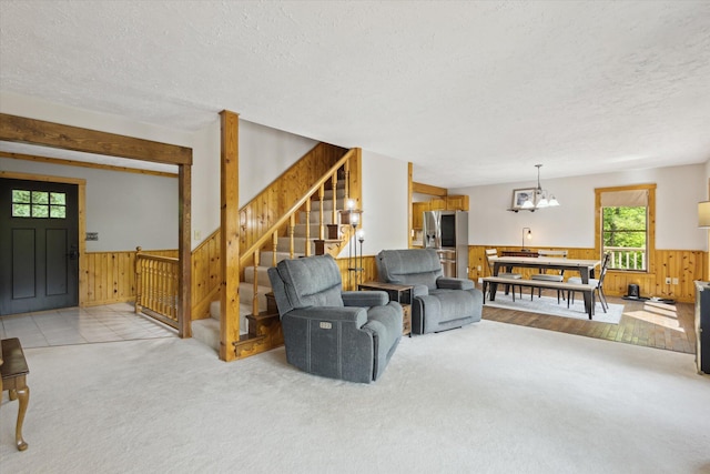 6860 Ashley Ave NE, Belding, MI 48809 - carpeted living room featuring wood walls, a textured ceiling, wainscoting, stairs, and a chandelier