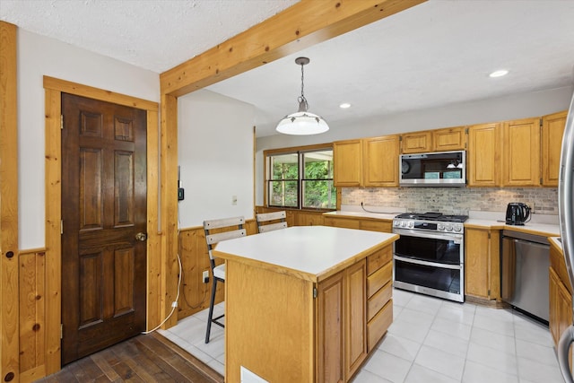 6860 Ashley Ave NE, Belding, MI 48809 - kitchen with stainless steel appliances, light countertops, wainscoting, a kitchen island, and tasteful backsplash