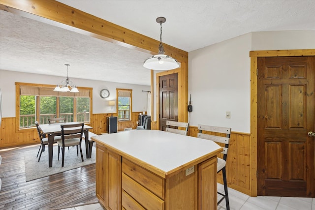 6860 Ashley Ave NE, Belding, MI 48809 - kitchen with wainscoting, wooden walls, a kitchen island, light countertops, and hanging light fixtures