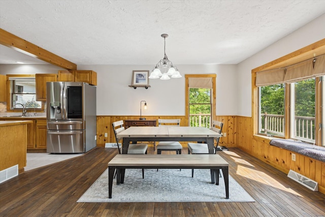 6860 Ashley Ave NE, Belding, MI 48809 - dining space with wainscoting, a chandelier, healthy amount of natural light, light wood-style floors, and wooden walls