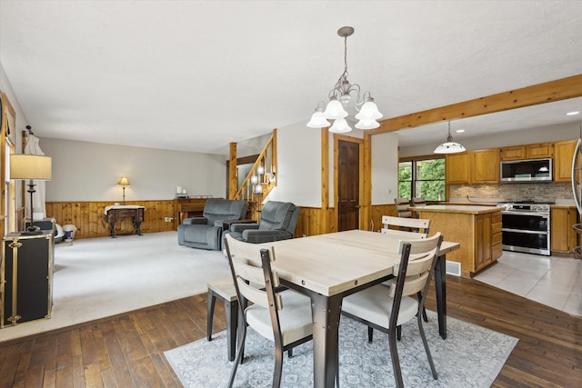 6860 Ashley Ave NE, Belding, MI 48809 - dining area featuring a wainscoted wall, wooden walls, stairway, light wood finished floors, and a chandelier