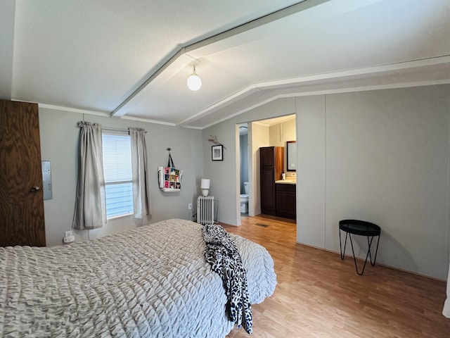5355 Meadowmoor Dr NE, Belmont, MI 49306 - bedroom with radiator heating unit, light wood-style floors, vaulted ceiling, and ensuite bath