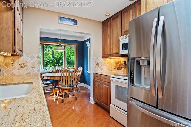 34030 Hampshire St, Livonia, MI 48154 - kitchen with white appliances, light wood-style floors, backsplash, light stone counters, and brown cabinetry