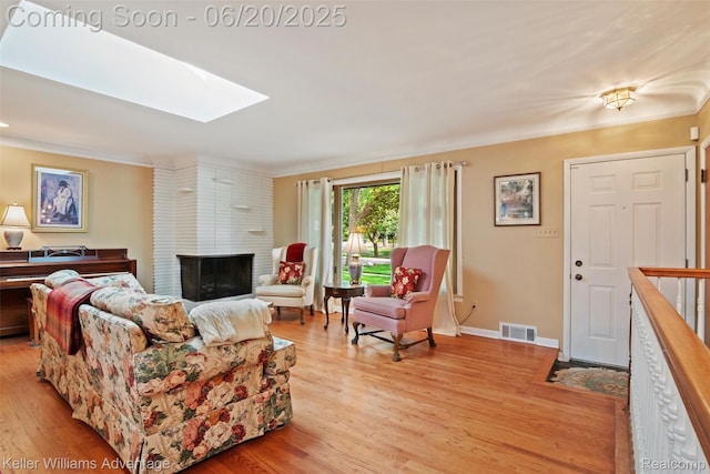 34030 Hampshire St, Livonia, MI 48154 - living room featuring a fireplace, a skylight, ornamental molding, and light wood-style floors