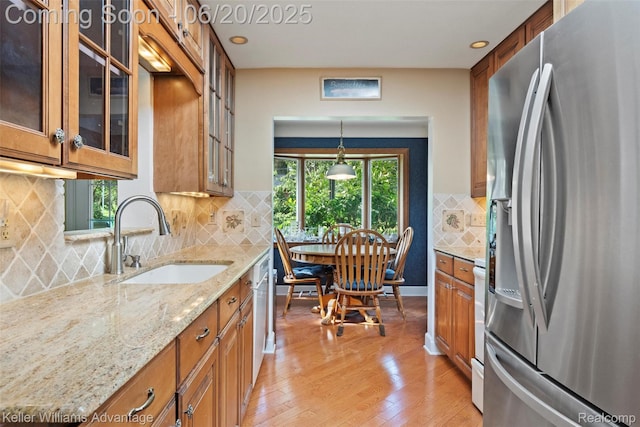 34030 Hampshire St, Livonia, MI 48154 - kitchen with stainless steel appliances, brown cabinetry, light wood-style floors, light stone countertops, and glass insert cabinets