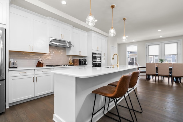 2949 Aughton Rd, Ann Arbor, MI 48105 - kitchen featuring under cabinet range hood, double oven, dark wood-style flooring, backsplash, and light countertops