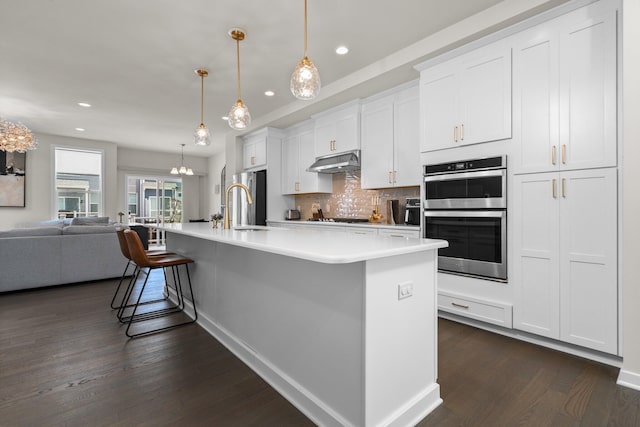 2949 Aughton Rd, Ann Arbor, MI 48105 - kitchen with under cabinet range hood, stainless steel appliances, dark wood-style flooring, open floor plan, and recessed lighting