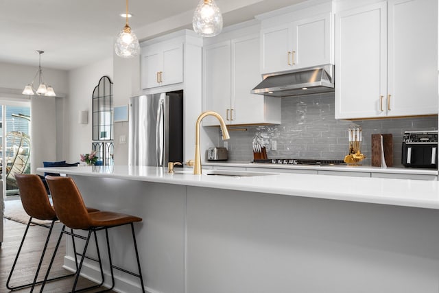 2949 Aughton Rd, Ann Arbor, MI 48105 - kitchen with appliances with stainless steel finishes, under cabinet range hood, backsplash, and a breakfast bar