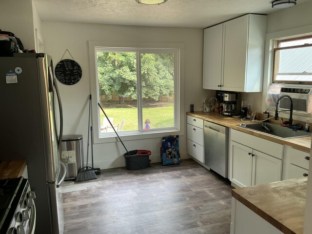2383 Holton Rd, Muskegon, MI 49445 - kitchen with stainless steel appliances, wood counters, healthy amount of natural light, white cabinetry, and a textured ceiling