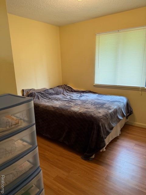 5496 Elizabeth Lake Rd, Waterford, MI 48327 - bedroom with light wood-type flooring and a textured ceiling