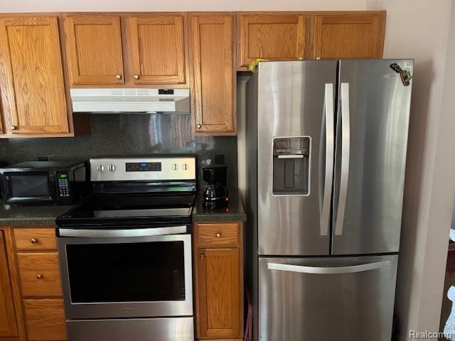 912 Rikki Anne Ct, Wixom, MI 48393 - kitchen with stainless steel appliances, under cabinet range hood, dark countertops, and brown cabinets