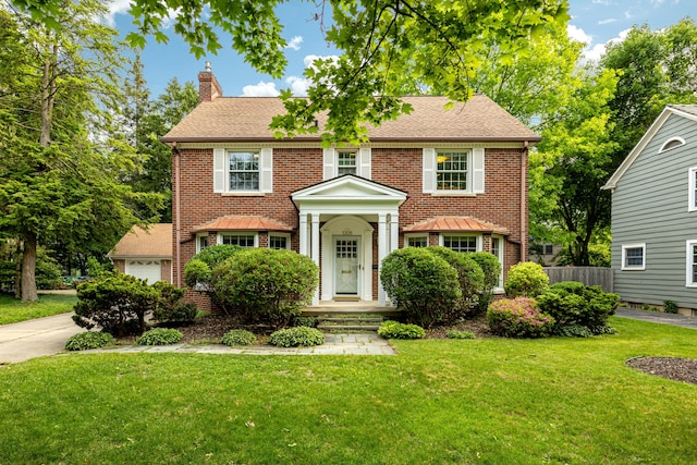 1208 Whittier Rd, Ypsilanti, MI 48197 - colonial-style house featuring a chimney, brick siding, a garage, and a shingled roof