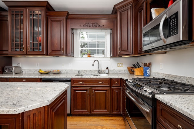 1208 Whittier Rd, Ypsilanti, MI 48197 - kitchen featuring stainless steel appliances, light wood finished floors, light stone counters, and glass insert cabinets