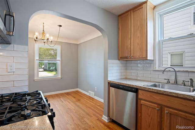 3434 Campbell St, Dearborn, MI 48124 - kitchen with stainless steel appliances, arched walkways, light wood-style floors, and backsplash