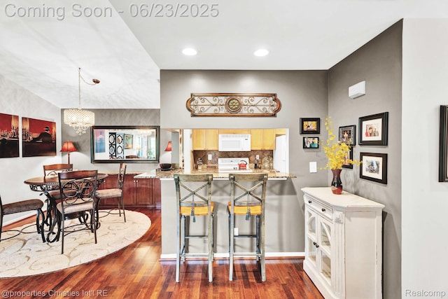 3581 Oakmonte Blvd Unit 60, Rochester, MI 48306 - kitchen with white microwave, dark wood-style flooring, a peninsula, a chandelier, and backsplash
