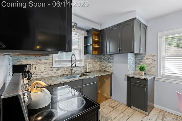 16136 Whitcomb St, Detroit, MI 48235 - kitchen with black electric range, tasteful backsplash, light stone counters, light wood-style floors, and gray cabinetry