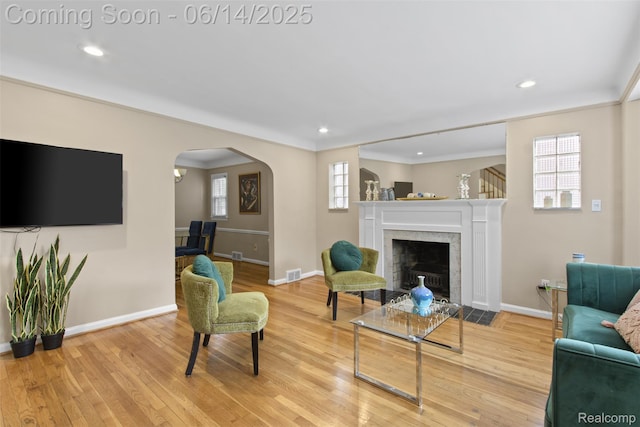 16136 Whitcomb St, Detroit, MI 48235 - living area featuring light wood finished floors, a fireplace with flush hearth, crown molding, arched walkways, and recessed lighting