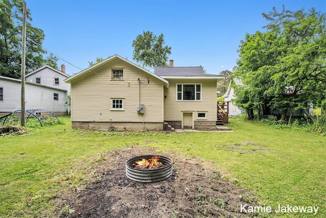 947 W Main St, Ionia, MI 48846 - rear view of property with a fire pit, a yard, stairway, and a chimney