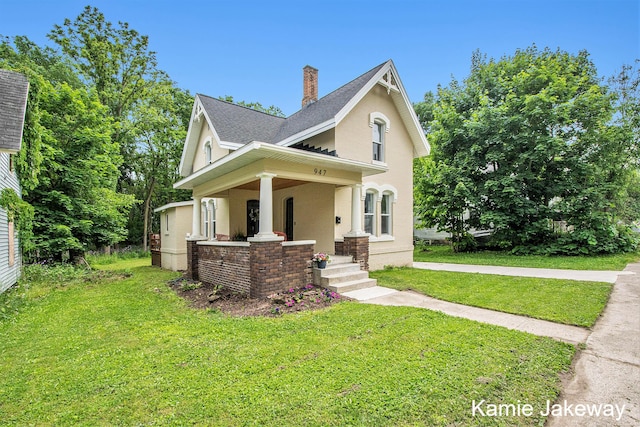 947 W Main St, Ionia, MI 48846 - view of front facade featuring a front lawn, a chimney, a porch, brick siding, and a shingled roof
